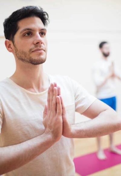 Group of people performing tree-pose yoga exercise in the fitness studio